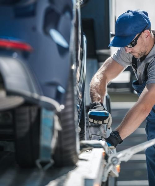towing-company-worker-securing-vehicle-on-the-truck-platform.jpg